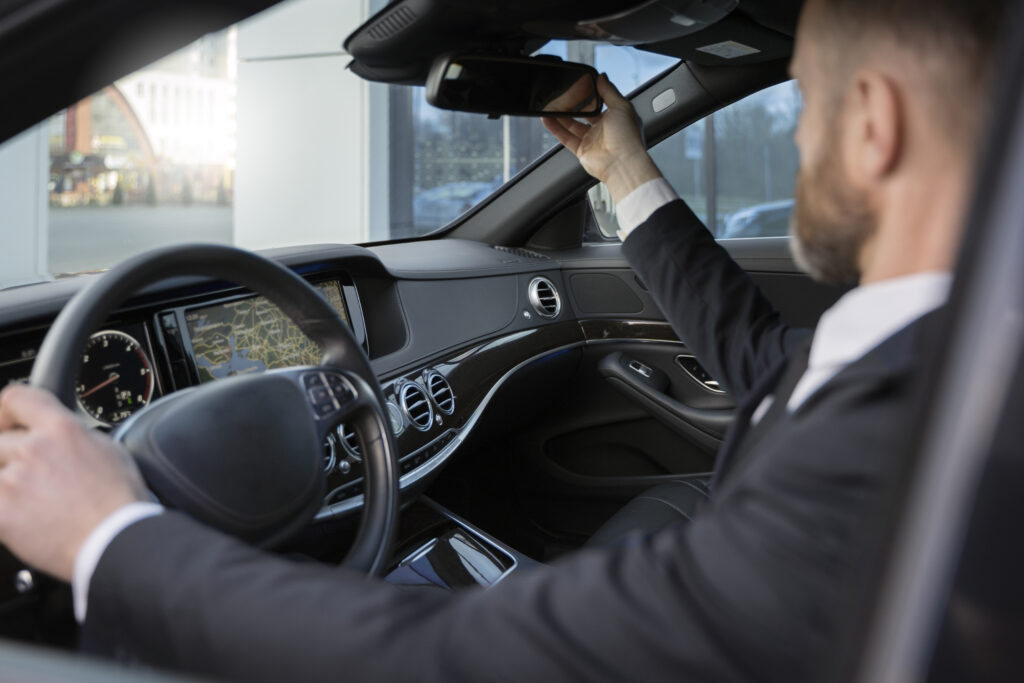 Black stretch limousine with chauffeur parked curbside – local limo hire service

