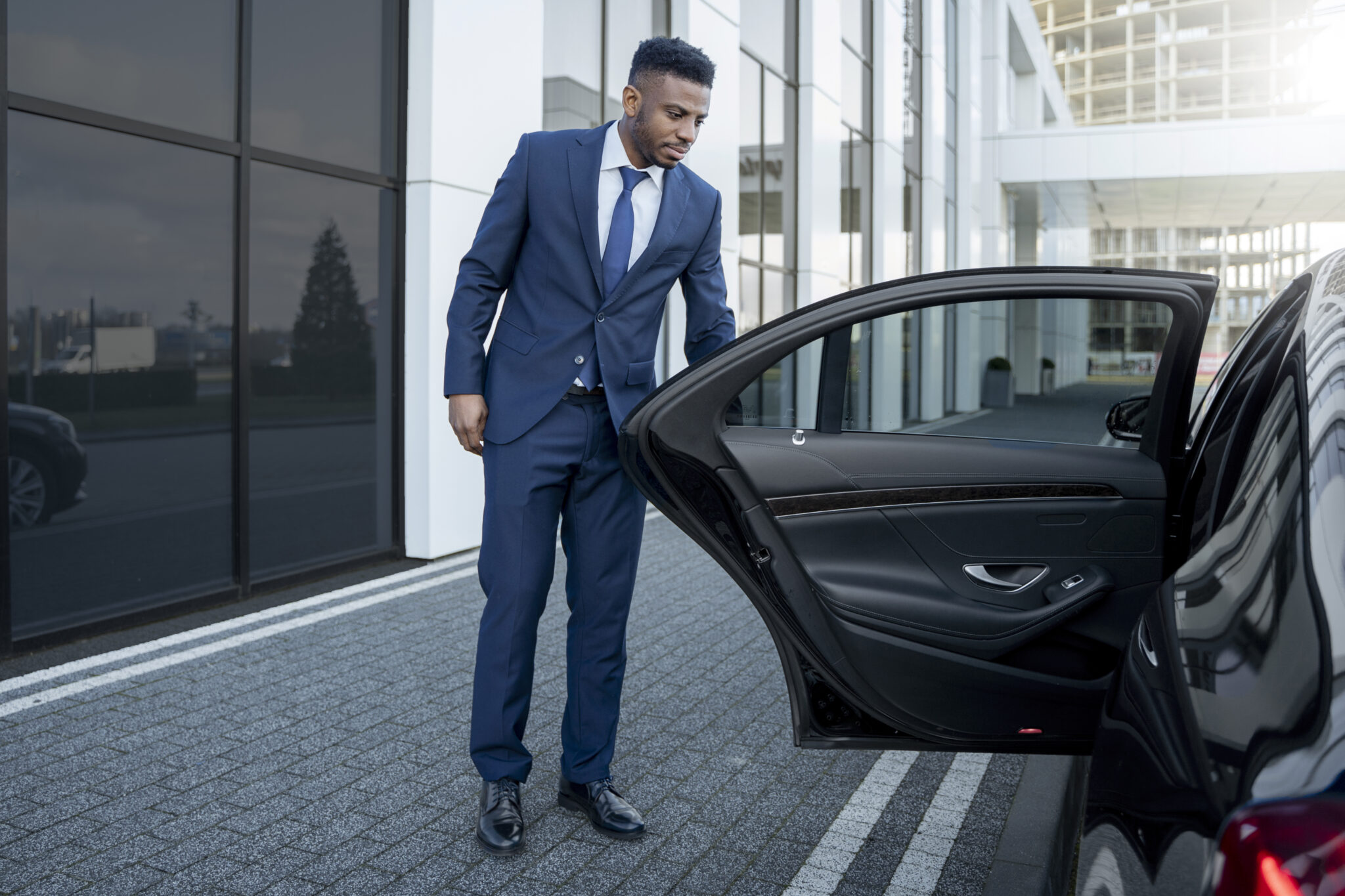 Luxury limousine waiting curbside in Brisbane with chauffeur opening the door, ready for passenger pickup.