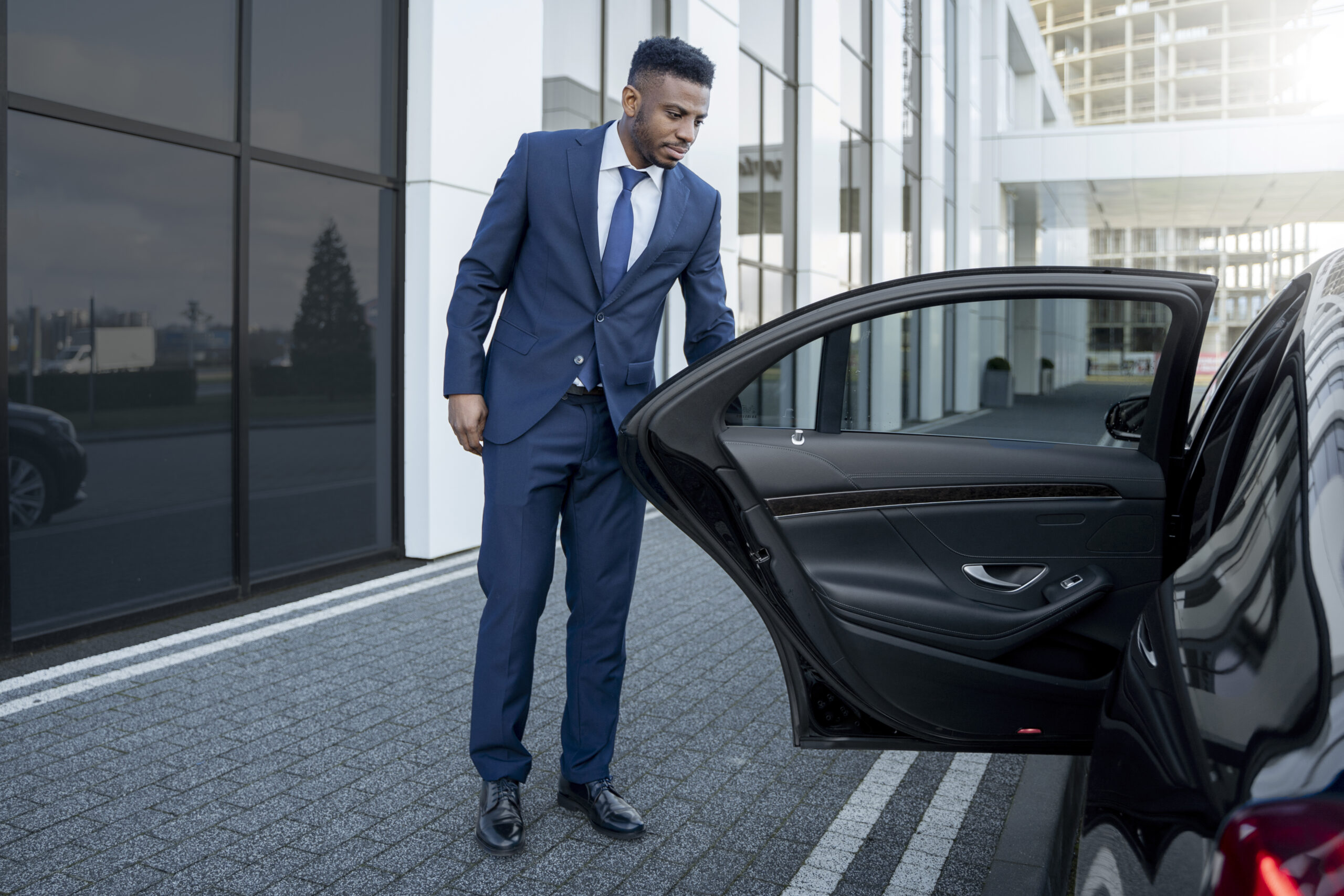 Luxury limousine waiting curbside in Brisbane with chauffeur opening the door, ready for passenger pickup.