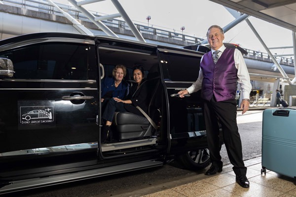 Airport transfer chauffeur assisting passenger at terminal with professional vehicle