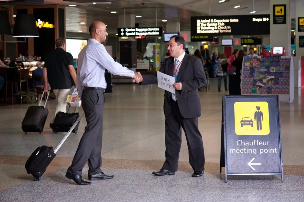 Chauffeur meeting passenger inside airport arrivals area